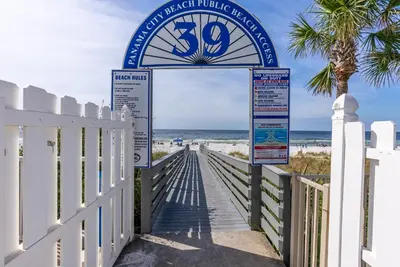 a boardwalk to the beach with a sign for the beach at Gulf Highlands-Sunset On The Gulf in Panama City Beach