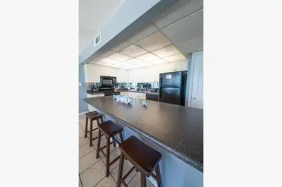 a kitchen with a long counter with stools in it at Edgewater 2-1107 'Making Memories' in Panama City Beach