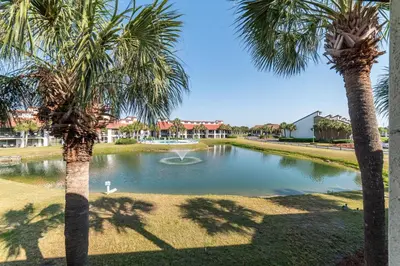 a pond with a fountain in a park with palm trees at Edgewater Villa 1105 'Villa Ardea' in Panama City Beach