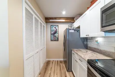a kitchen with white cabinets and a refrigerator at Edgewater Villa 1101 'Sunset Paradise At Edgewater' in Panama City Beach