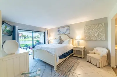 a bedroom with a bed and a chair and a window at Edgewater Villa 1101 'Sunset Paradise At Edgewater' in Panama City Beach
