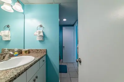 a bathroom with a sink and a blue wall at Sunbird 0703E 'Beachhead Paradise' in Panama City Beach