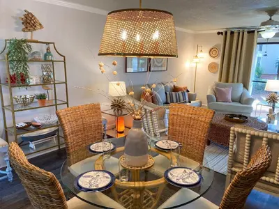 a living room with a glass table and wicker chairs at Edgewater Villa 2901 'Tipsy Turtle' in Panama City Beach