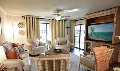 a living room with a tv and a couch and chairs at Edgewater Villa 2901 'Tipsy Turtle' in Panama City Beach