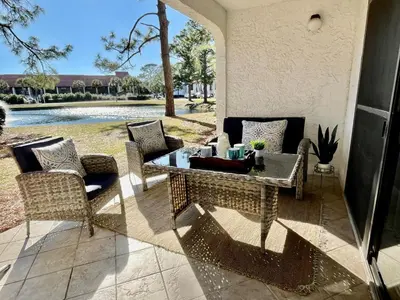 a patio with a table and chairs next to a pool at Edgewater Villa 2901 'Tipsy Turtle' in Panama City Beach