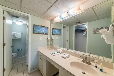 a bathroom with a sink and a toilet and a mirror at Edgewater Villa 2006 'Sandy Shores Hideaway' in Panama City Beach