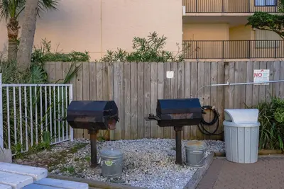 two bbq equipment in front of a wooden fence at Top Of The Gulf 312 'The Tip-Sea Turtle' in Panama City Beach