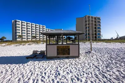 a gazebo on a sandy beach with a building at Top Of The Gulf 312 'The Tip-Sea Turtle' in Panama City Beach