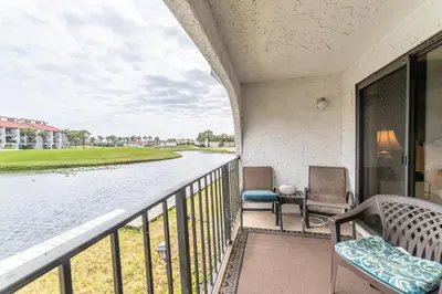 a balcony with two chairs and a body of water at Edgewater Villa 0402 'Serenity Now' in Panama City Beach