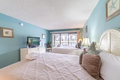 a bedroom with two beds and a television in it at Edgewater Villa 0402 'Serenity Now' in Panama City Beach