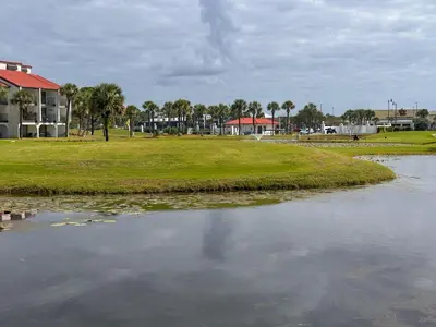 a body of water with a building and palm trees at Edgewater Villa 0402 'Serenity Now' in Panama City Beach
