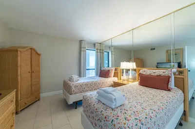 a bedroom with two beds and a large mirror at Edgewater 1-1212 'Combee's Penthouse HideAway' in Panama City Beach