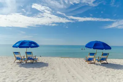 two blue chairs and two umbrellas on a beach at Edgewater Villa 0903 'Heron Landing' in Panama City Beach