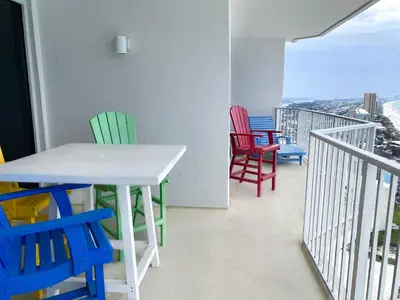 a balcony with colorful chairs and a white table and chairs at Boardwalk 2201 'Sea Serenity Penthouse' in Panama City Beach