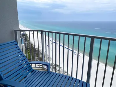 a blue bench sitting on a balcony overlooking the beach at Boardwalk 2201 'Sea Serenity Penthouse' in Panama City Beach