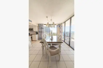 a dining room with a table and chairs and a balcony at Edgewater L200 'Wish Upon A Starfish' in Panama City Beach