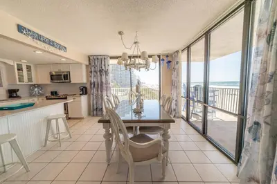 a kitchen and dining room with a table and a balcony at Edgewater L200 'Wish Upon A Starfish' in Panama City Beach