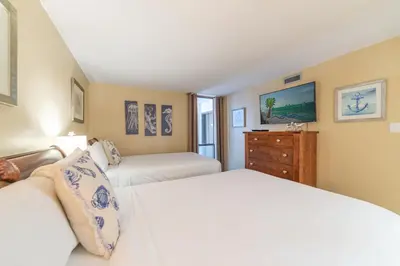 a bedroom with two beds and a dresser at Edgewater L200 'Wish Upon A Starfish' in Panama City Beach