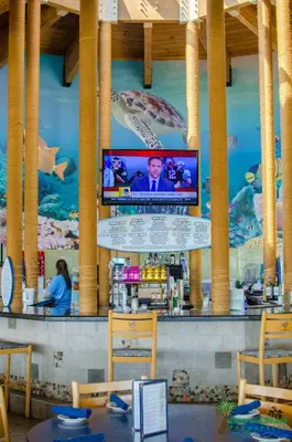 a bar with a television on the wall of a restaurant at Edgewater L200 'Wish Upon A Starfish' in Panama City Beach