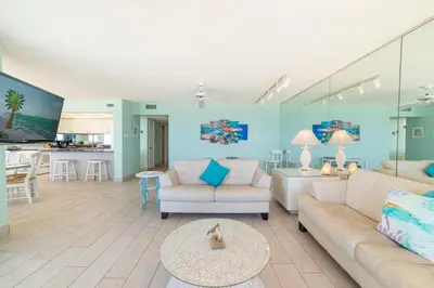 a living room with blue walls and white furniture at Edgewater L608 'Turquoise Turtle' in Panama City Beach