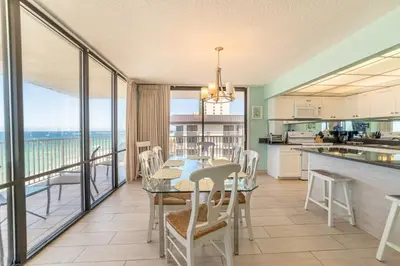 a kitchen and dining room with a table and a balcony at Edgewater L608 'Turquoise Turtle' in Panama City Beach