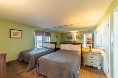 two beds in a bedroom with green walls and wooden floors at Edgewater 3-0814 'Pelican Watch' in Panama City Beach