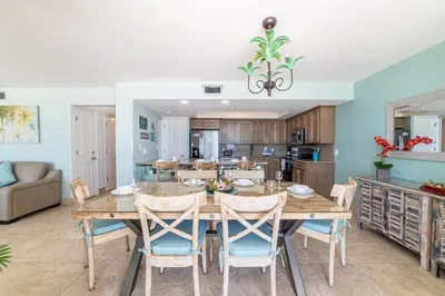 a dining room and kitchen with a wooden table and chairs at Edgewater 3-0613 'Solace' in Panama City Beach