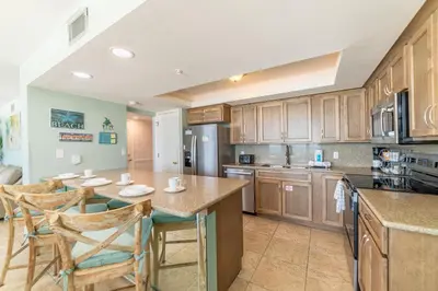 a kitchen with wooden cabinets and a large island at Edgewater 3-0613 'Solace' in Panama City Beach