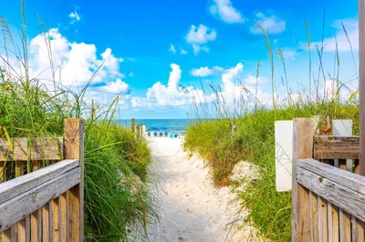 a path to a beach with a fence and the ocean at Mariner West 605 'Flip Flops & Sunsets' in Panama City Beach