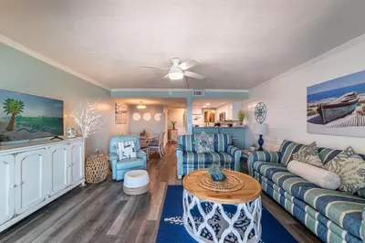 a living room with a couch and a table at Mariner West 605 'Flip Flops & Sunsets' in Panama City Beach
