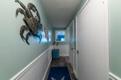 a hallway with a painting of a lobster on the wall at Mariner West 605 'Flip Flops & Sunsets' in Panama City Beach