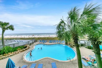 a swimming pool with palm trees and a beach at Edgewater Tower 2-108-Gunners Paradise in Panama City Beach