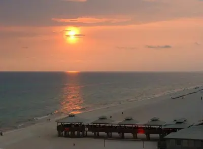 a sunset over a beach with a pier and the ocean at Top Of The Gulf 316 'Coastal View' in Panama City Beach