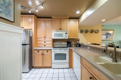 a kitchen with white appliances and wooden cabinets at Edgewater Villa 0955 'Fountain of Youth' in Panama City Beach