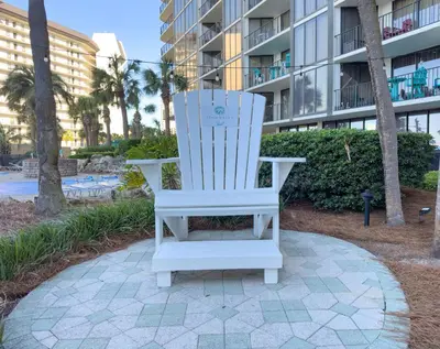a white rocking chair in front of a building at Edgewater Villa 3011 'Fountain View Hideaway' in Panama City Beach