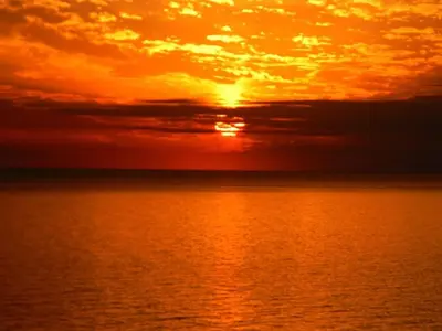 an orange sunset over the ocean with the sun setting at Edgewater Villa 3011 'Fountain View Hideaway' in Panama City Beach