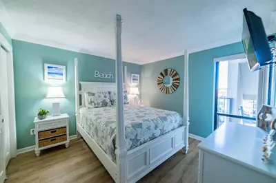 a bedroom with a bed and a bathroom with a window at Edgewater 2-0602 'Beach Blessings' in Panama City Beach