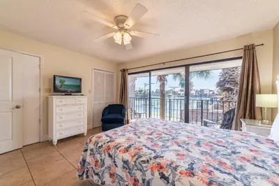 a bedroom with a bed and a tv and a balcony at Edgewater Villa 3007 'Anchors Away' in Panama City Beach