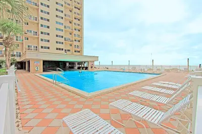 a swimming pool with lounge chairs next to a hotel at Pinnacle Port B3-408-Emerald Pearl in Panama City Beach