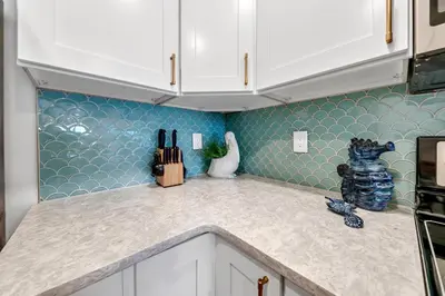 a kitchen with white cabinets and blue tiles at Pinnacle Port B3-408-Emerald Pearl in Panama City Beach