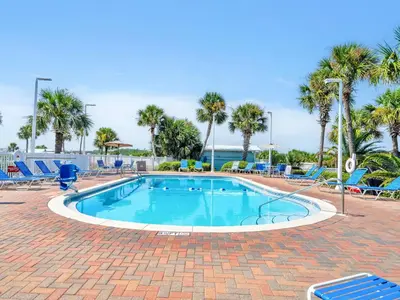 a swimming pool with blue chairs and palm trees at Pinnacle Port B3-408-Emerald Pearl in Panama City Beach