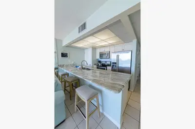 a kitchen with a counter with stools in it at Edgewater 1-0708 'Beach Happy' in Panama City Beach