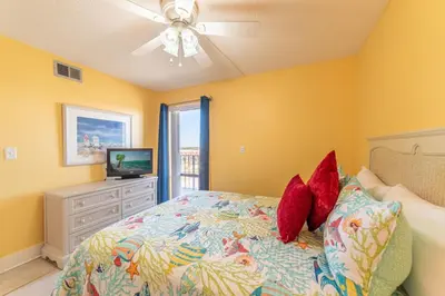 a bedroom with yellow walls and a bed with red pillows at Edgewater 3-0905 'Gone Coastal' in Panama City Beach