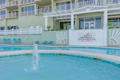 a swimming pool with a fountain in front of a hotel at Boardwalk 1409 'Emerald Ray' in Panama City Beach