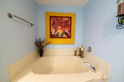 a white bath tub in a bathroom with a painting at Boardwalk 0810 'Endless Summer' in Panama City Beach
