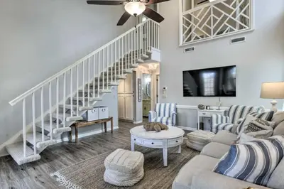 a living room with a couch and a staircase at Cozy Beach Condo in Panama City Beach