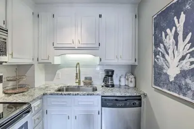a kitchen with white cabinets and a sink at Cozy Beach Condo in Panama City Beach