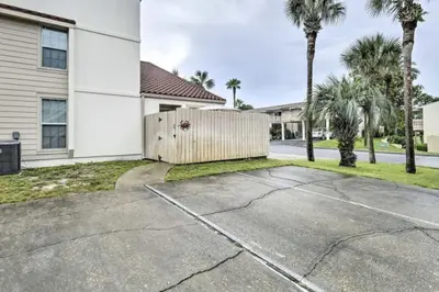 a house with a fence and palm trees at Cozy Beach Condo in Panama City Beach