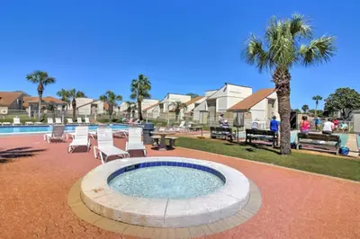 a swimming pool with lounge chairs and a palm tree at Cozy Beach Condo in Panama City Beach