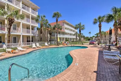 a swimming pool in front of a building with palm trees at Cozy Beach Condo in Panama City Beach